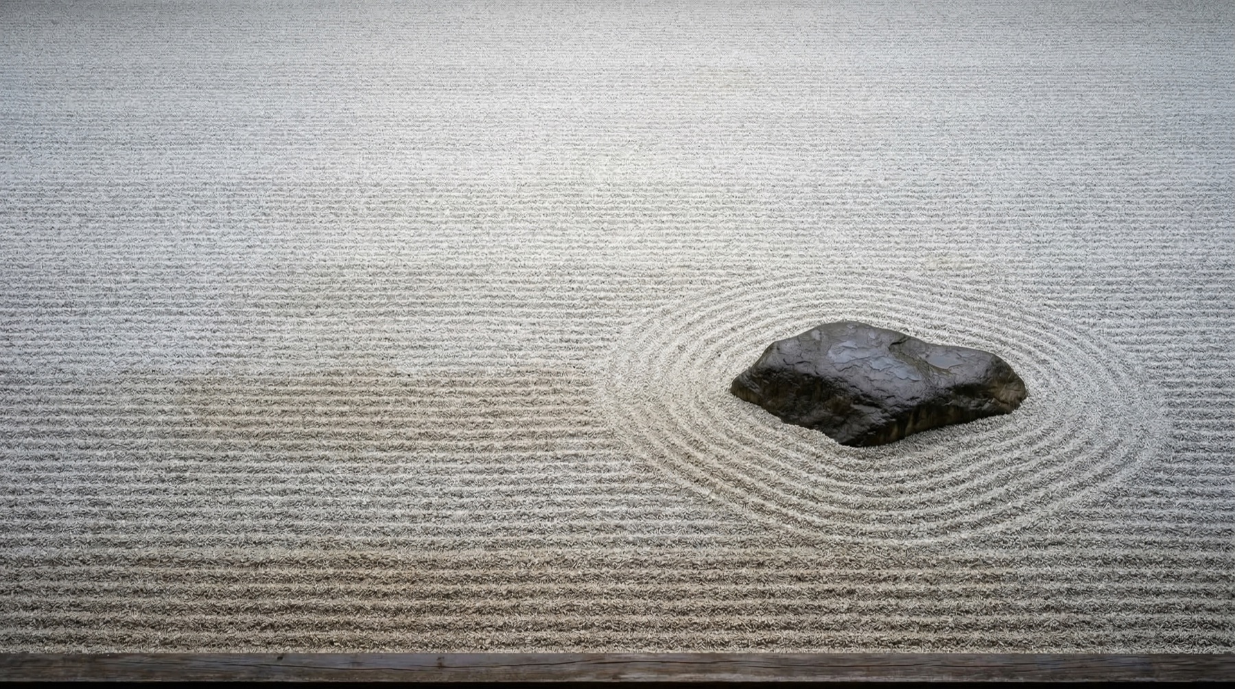 Zen garden — raked gravel with single stone, composition through reduction
